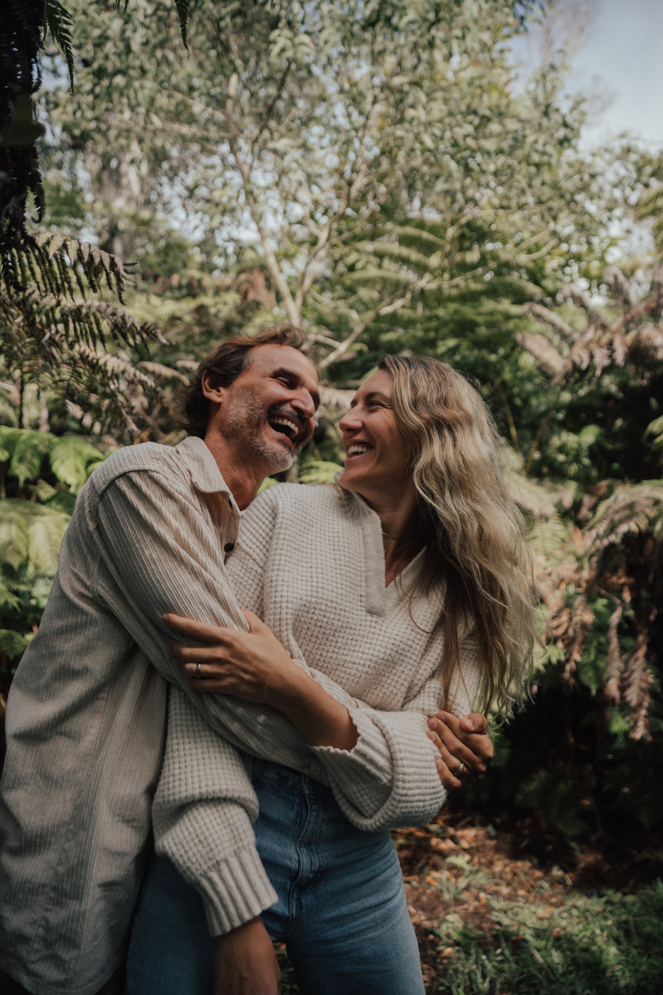 A couple laughing in each other's arms in the forest